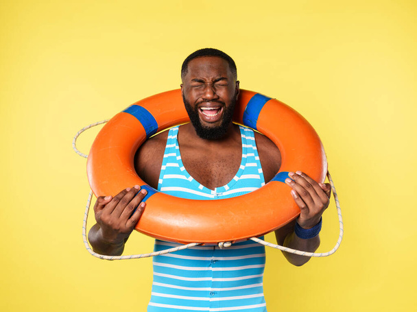 Man with lifebelt is scared to swim. yellow background - Photo, Image