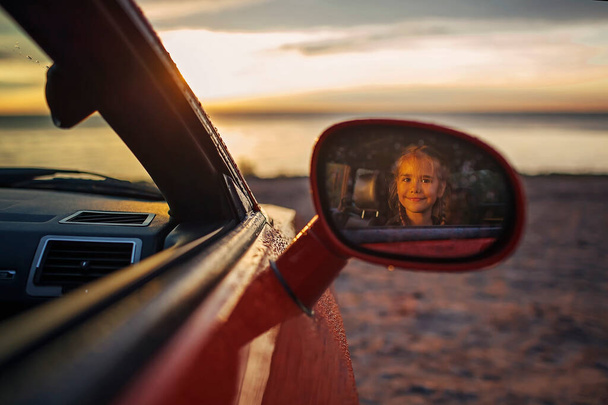 Vapaus ja perhematkustaja. Tyttö istuu autossa meren rannalla sateen jälkeen - Valokuva, kuva