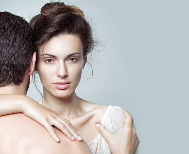 Sexy couple of muscular man embracing with back and pretty woman or girl in studio on grey background. - Φωτογραφία, εικόνα