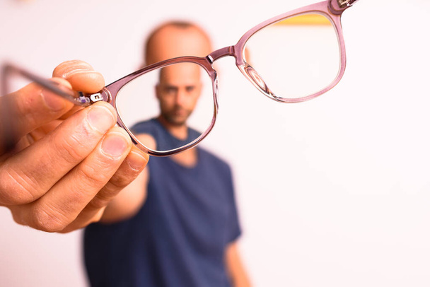 Felnőtt férfi tartja asztigmatizmus szemüveg műanyag polimer lencsék. - Fotó, kép