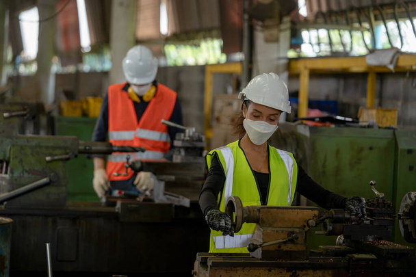 Les ouvriers d'usine portent le masque facial travaillent avec la machine sur l'usine de l'industrie. - Photo, image