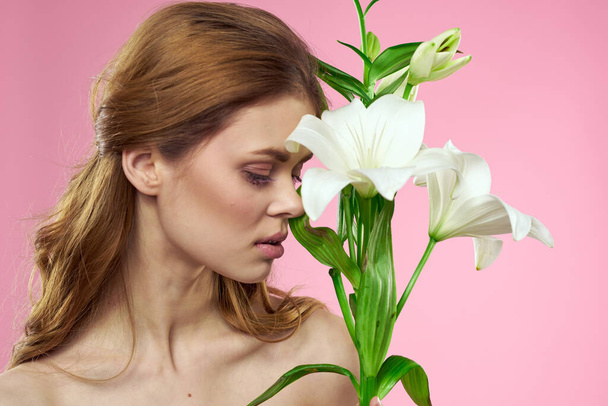 Portrét krásné ženy s bílými květy v rukou na růžovém pozadí  - Fotografie, Obrázek