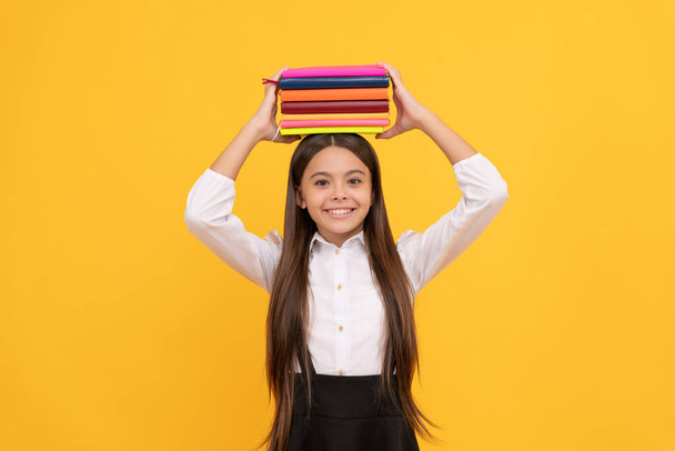 szczęśliwy nastolatek dziewczyna w szkole mundur trzymać książki stos, wiedza. - Zdjęcie, obraz