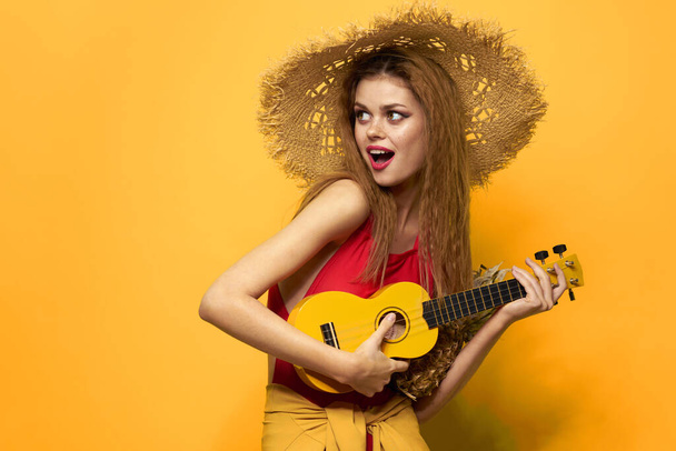 mujer en rojo sombrero ukelele en manos estilo de vida verano rojo camiseta amarillo fondo - Foto, imagen