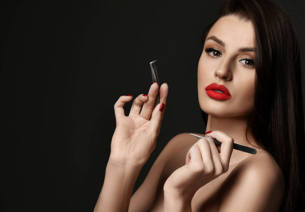 Portrait of wealthy naked luxury woman with red lips and makeup holding cosmetologist tools tweezers for lash and brow - Φωτογραφία, εικόνα