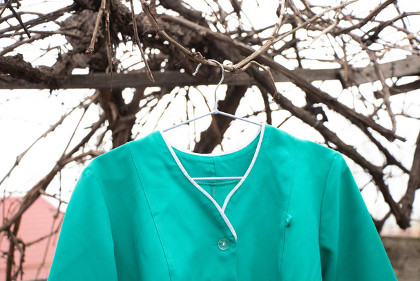 старый медицинский костюм висит на вешалке на улице в Украине, униформа медсестры - Фото, изображение