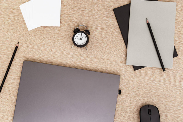 Desktop for student or freelancer. Working space. Workplace with grey modern laptop, cup of coffee, glasses and clock for time control on light table. Flat lay. - Foto, Imagen