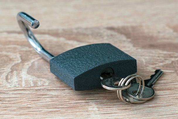avoin lukko, jossa on avaimet avaimenreiässä puupinnalla. Laadukas kuva - Valokuva, kuva