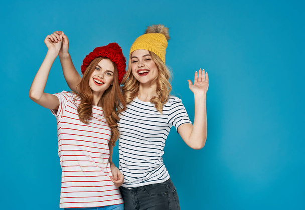 Renkli şapkalı iki arkadaş dostluk iletişimi mavi arka plan - Fotoğraf, Görsel