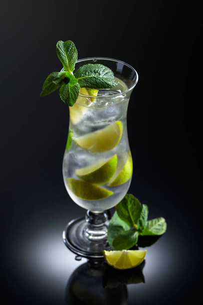 Mojito cocktail with ice, lime, and mint on a black reflective background. - Foto, Imagem