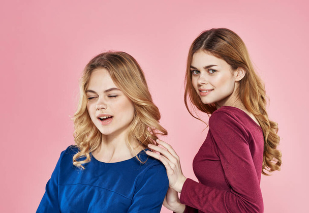 Две элегантные девушки обнимают общение роскошь жизни розовый фон - Фото, изображение