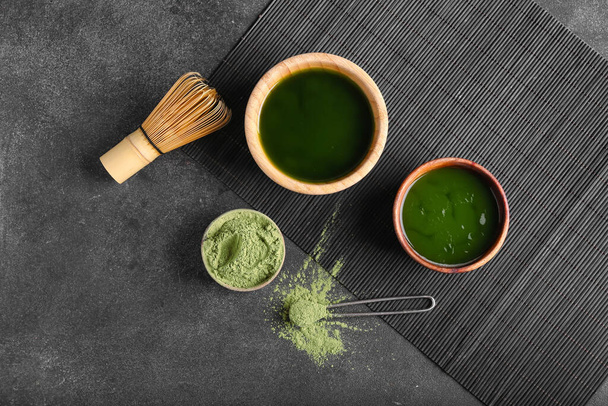 Bowls with matcha tea, powder and chasen on dark background - Photo, Image
