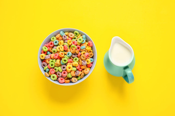 Mísa s obilovinami a džbánek mléka na barevném pozadí - Fotografie, Obrázek