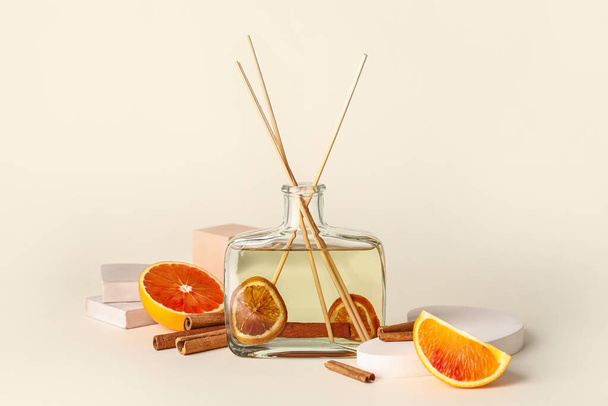 Reed diffuser with cinnamon and grapefruits on light background - Fotoğraf, Görsel