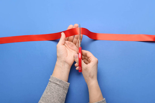 Woman cutting red ribbon on color background - Photo, Image