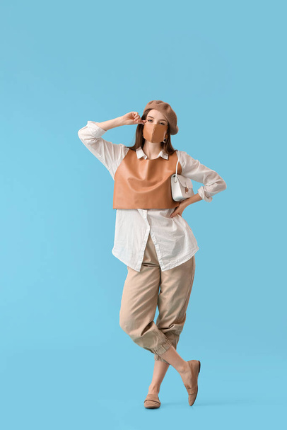 Fashionable young woman wearing mask on color background - Valokuva, kuva