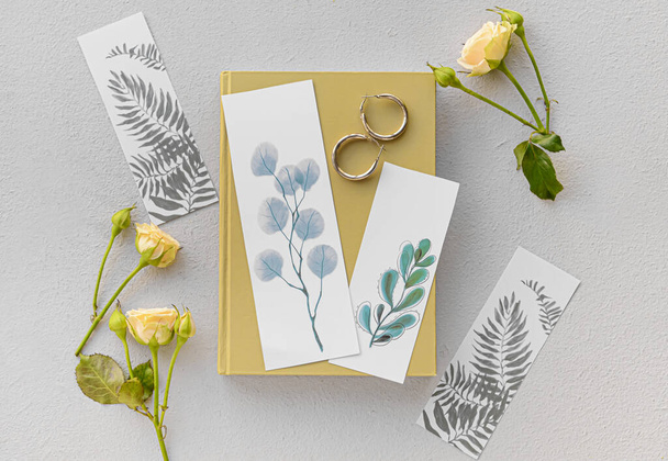 Book with bookmarks and flowers on light background - Fotoğraf, Görsel