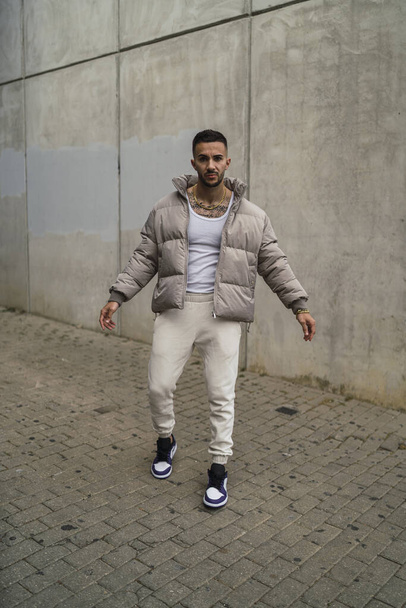 A vertical shot of a sexy male in a street style outfit posing outdoors - Zdjęcie, obraz