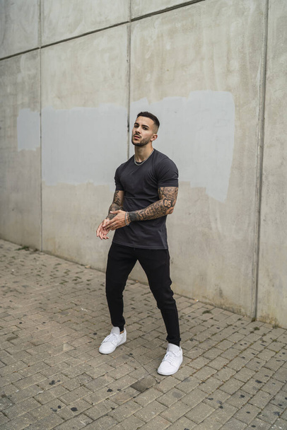A vertical shot of a sexy male in a street style outfit posing outdoors - Fotoğraf, Görsel
