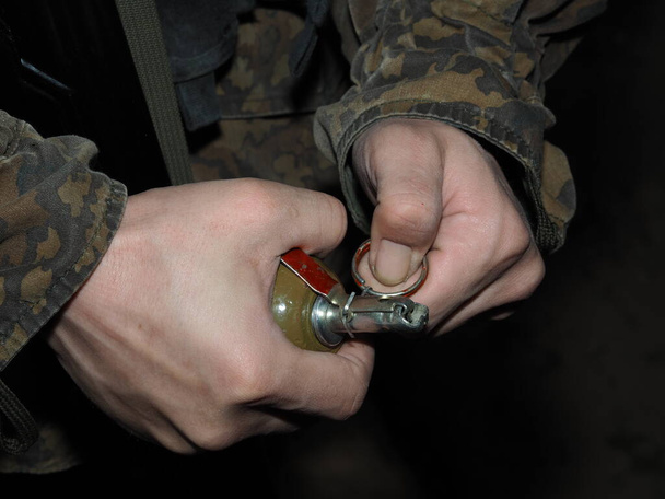 Στρατιωτικός άνδρας κρατά (δείχνει, απειλεί) στο χέρι του μια μάχη, χειροβομβίδα επιθετικού τύπου. Εθελοντής στο Ουκρανικό καμουφλάζ. Η έννοια της στρατιωτικής σύγκρουσης, του παγκόσμιου πολέμου, της τρομοκρατίας, ή εκκαθάριση των ναρκών. - Φωτογραφία, εικόνα