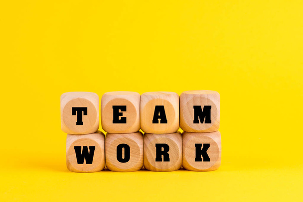 Teamwork in the company, the word teamwork on wooden blocks isolated on a yellow background - Fotoğraf, Görsel