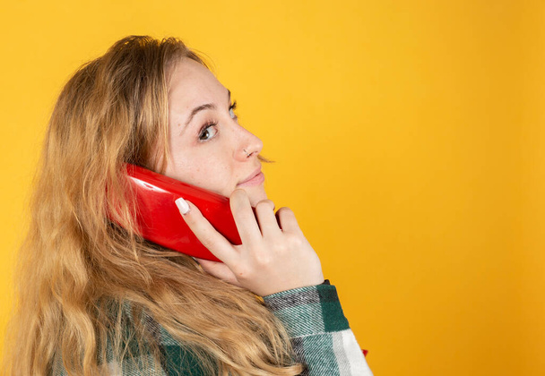ładna blondynka dziewczyna mówi na stary telefon na żółtym tle - Zdjęcie, obraz