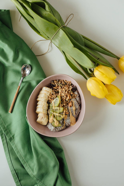 A flat lay shot of the healthy chia pudding on green cloth with yellow tulips. - 写真・画像