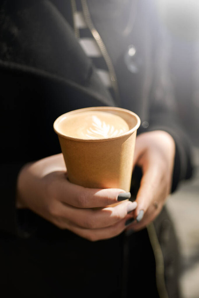 Kızın elinde kahve olan bir fincan. Kapuçinolu kağıt bardak ve kız eli. maket yap - Fotoğraf, Görsel