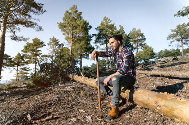 A lumberjack man is taking a break during the work in the woody terrai - Foto, afbeelding