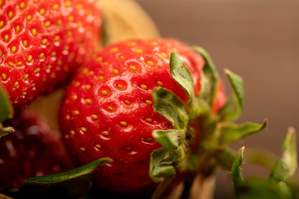 Fresh red strawberries in a wicker basket on a wooden table. Harvesting. Close-up, selective focus. - Foto, Bild