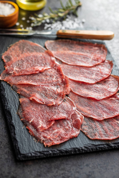 Sliced carpaccio. Raw beef meat on black cutting board. - Foto, Imagen