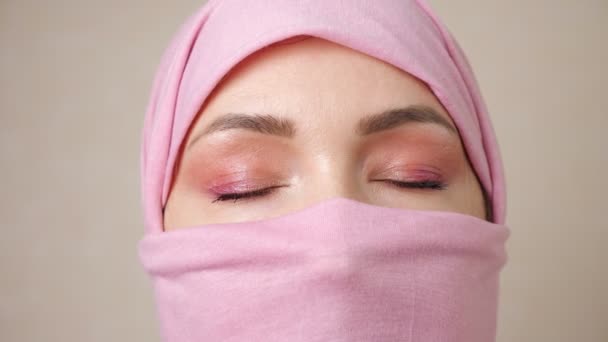 Muslimin mit rosafarbenem Kopftuch verdeckt Gesicht - Filmmaterial, Video