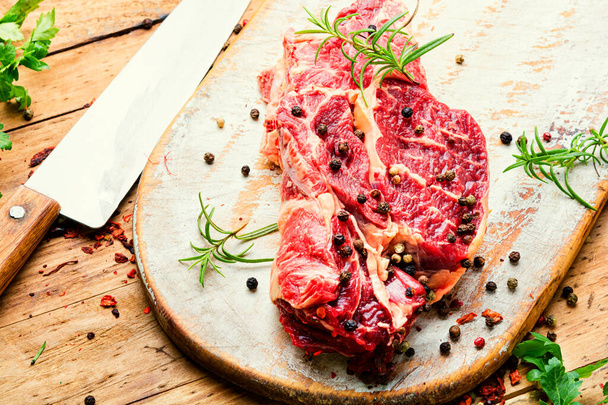 Raw beef meat with rosemary and spices on wooden cutting board - 写真・画像