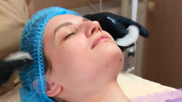 Καλλυντικός γιατρός σκούπισμα γυναίκα πρόσωπο χρησιμοποιεί βαμβάκι μαξιλάρια μετά τη διαδικασία ξεφλούδισμα. Γιατρός κάνει διαδικασία ομορφιάς στην κλινική κοσμετολογίας. Φροντίδα για το δέρμα του προσώπου - Πλάνα, βίντεο