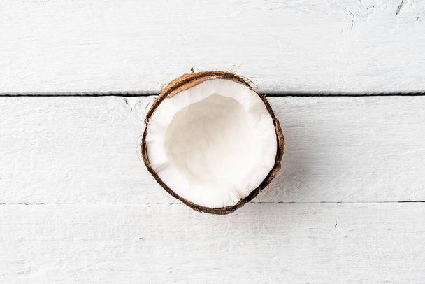 Half of fresh coconut on white wooden background. Top view - Foto, Imagen