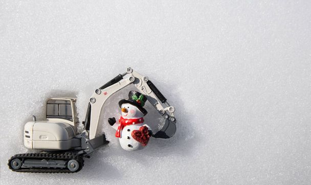 Metal oyuncak kazıcı, hatıra kardan adam, beyaz kar. Noel iş tebrikleri, inşaat şirketlerinde yeni yıl tatili konsepti. Boşluğu kopyala - Fotoğraf, Görsel