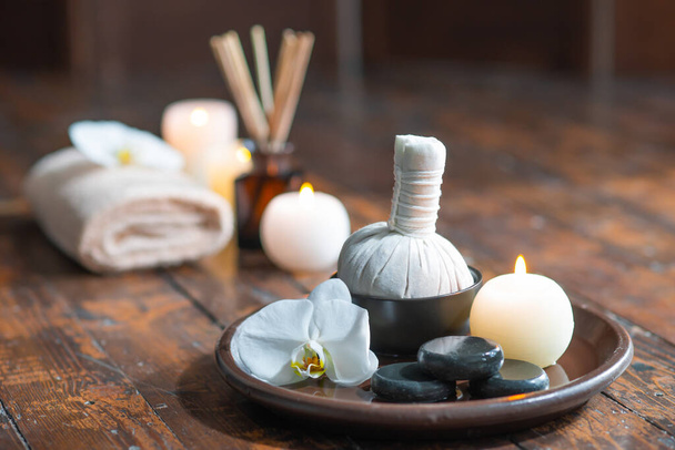 Spa background. Towel, candles, flowers, aroma sticks, massaging stones and herbal balls. Massage, oriental therapy, wellbeing and meditation. - Foto, Imagen