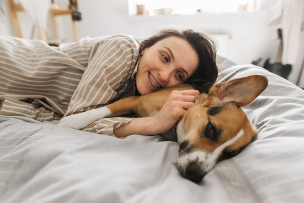 young woman with a dog in bed having fun in the morning - Φωτογραφία, εικόνα