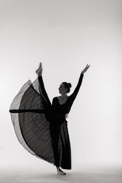 Portarit der sinnlichen professionellen kaukasischen Balletttänzerin in Body-Anzug und Spitzenschuhen posiert auf dem Boden auf weiß. - Foto, Bild