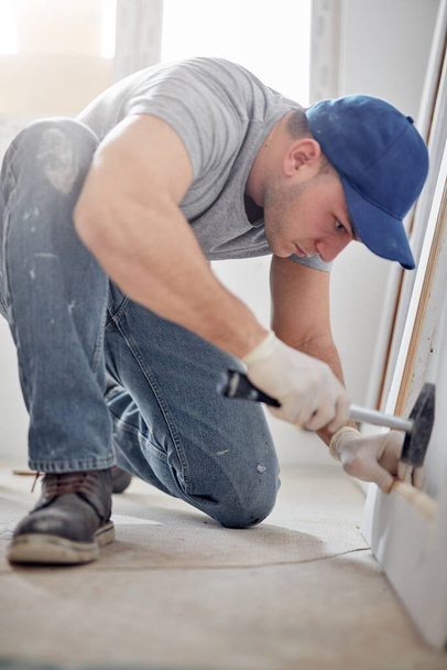 Молодой взрослый мужчина работает над ремонтом своей новой квартиры. - Фото, изображение