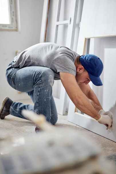 Homem adulto jovem trabalhando em uma renovação do orçamento DIY de seu novo apartamento em casa. - Foto, Imagem