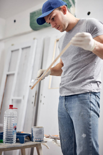 Mladý dospělý muž pracující na DIY rozpočtu renovace svého nového bytu. - Fotografie, Obrázek