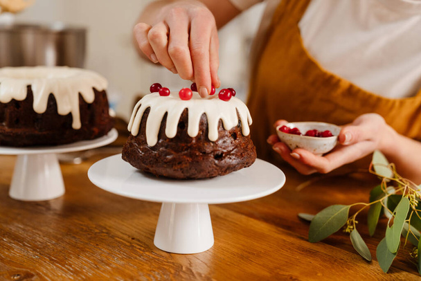Caucasian pastry chef woman making chocolate cake with berries at cozy kitchen - Foto, Bild