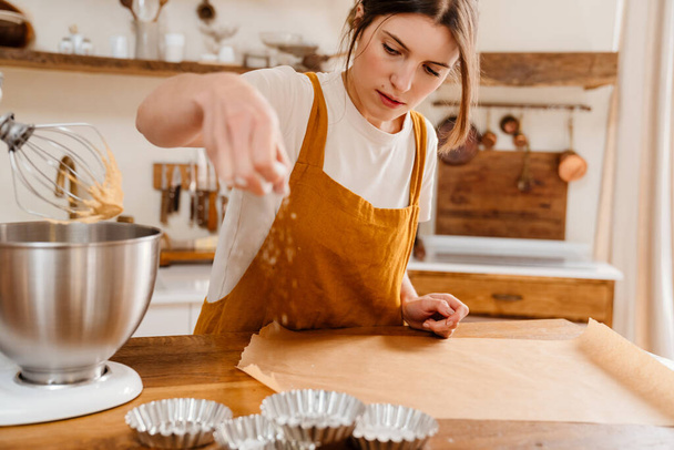 Beautiful focused pastry chef woman making tarts at cozy kitchen - 写真・画像