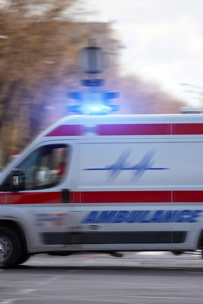 Ασθενοφόρο 911 ασθενοφόρο αυτοκίνητο τρέχει γρήγορα μέσα από τη μεγάλη πόλη. - Φωτογραφία, εικόνα