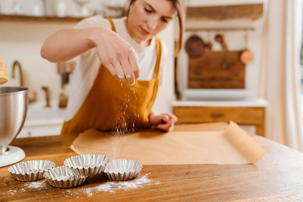 Beautiful focused pastry chef woman making tarts at cozy kitchen - Фото, изображение