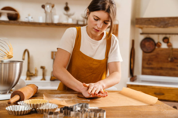 Caucasian focused pastry chef woman making dough at cozy kitchen - 写真・画像