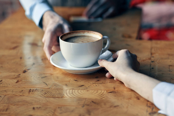 ο σεφ σερβίρει στον πελάτη ένα φλιτζάνι καφέ με ένα πιατάκι στο τραπέζι και ένα ποτό στο εστιατόριο - Φωτογραφία, εικόνα