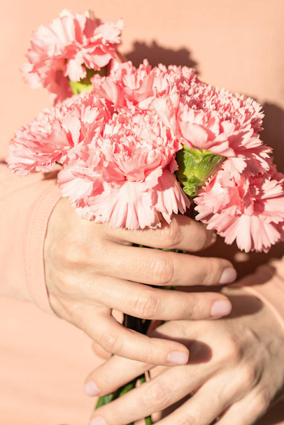 Mains de femmes tenant un bouquet d'œillets. - Photo, image
