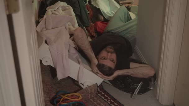 Hoarder zittend in een stapel rommel - Video